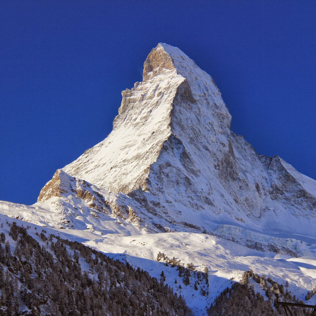 A striking view of the Matterhorn under a clear blue sky, showcasing its iconic peak and epitomizing the allure of Peak Travel destinations.