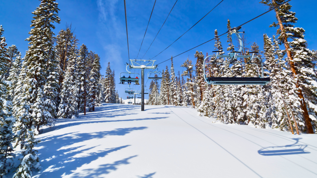 Ski lift on a clear bluebird day, surrounded by snow-covered slopes and bright sunshine, offering stunning views in a Colorado Ski Town