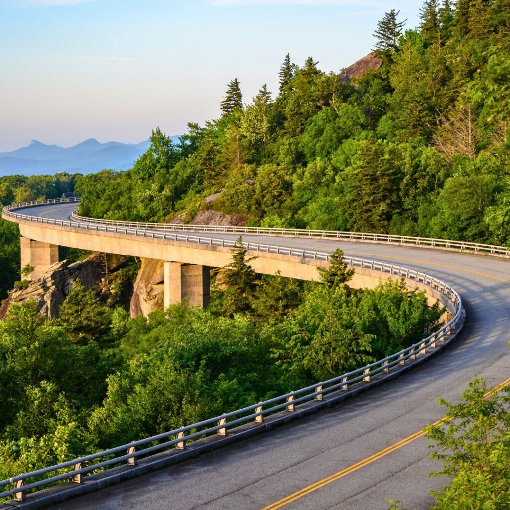 Blue Ridge Parkway winding through vibrant green foliage in the spring or summer, showcasing North Carolina as one of the best states to travel to in 2025.