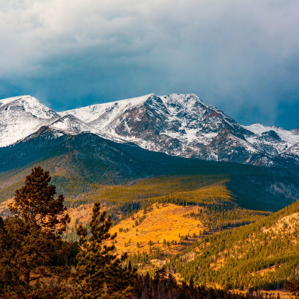 A breathtaking scenic view of the snowcapped Rocky Mountains, showcasing their rugged peaks and expansive beauty under a foggy sky.