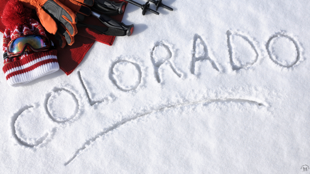 Colorado written in the snow with snow gear, including skis and poles, in the top left corner, capturing the spirit of winter in Colorado Ski Towns.