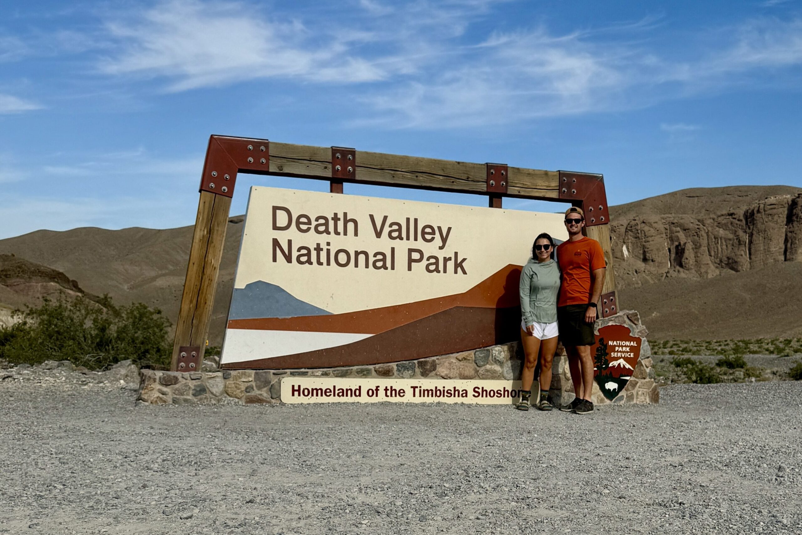 A couple posing with the iconic Death Valley National Park entrance sign, marking the start of their adventure in one of the hottest and driest places on Earth.