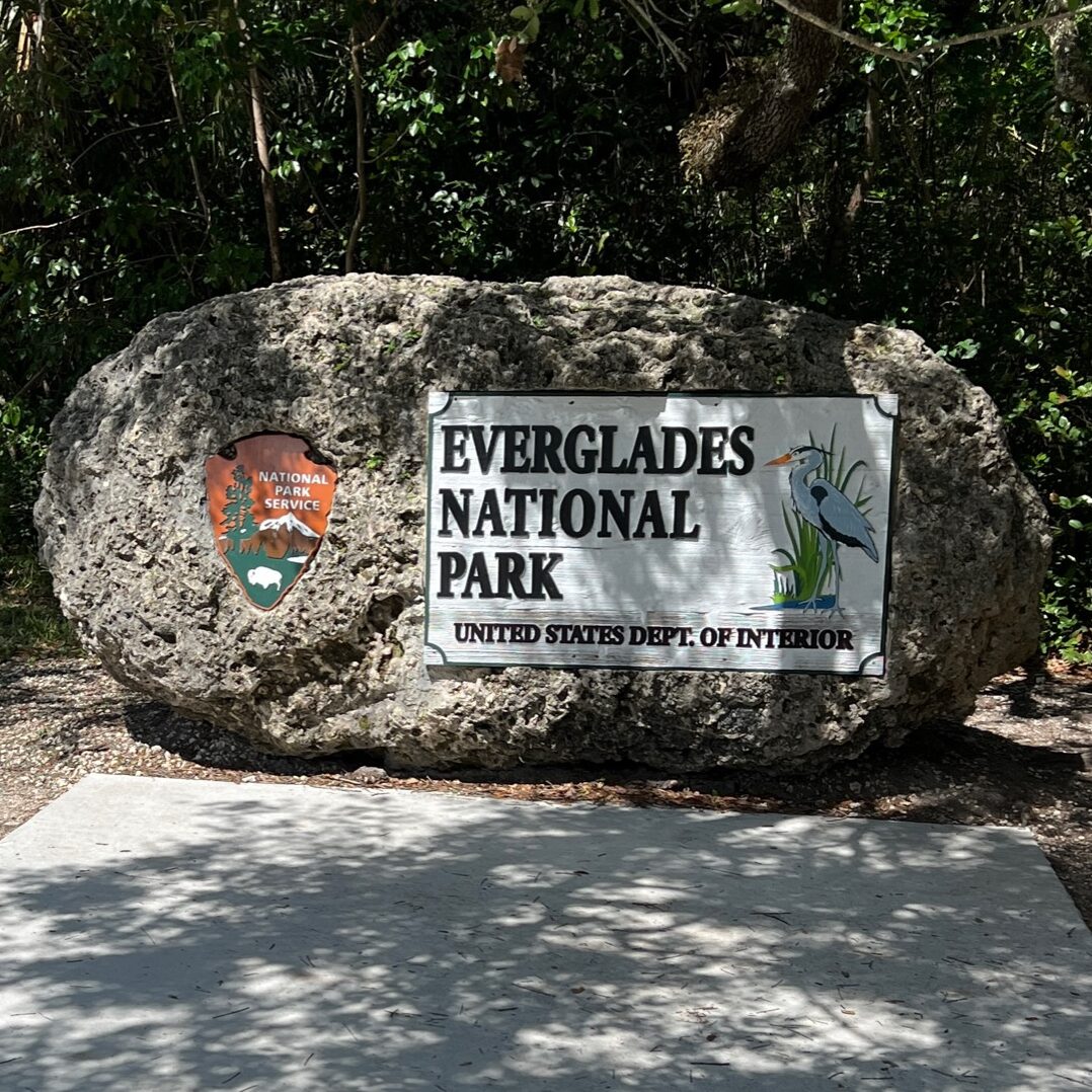 Everglades National Park entrance sign surrounded by lush greenery, welcoming visitors to the unique wetlands and diverse wildlife of the park.