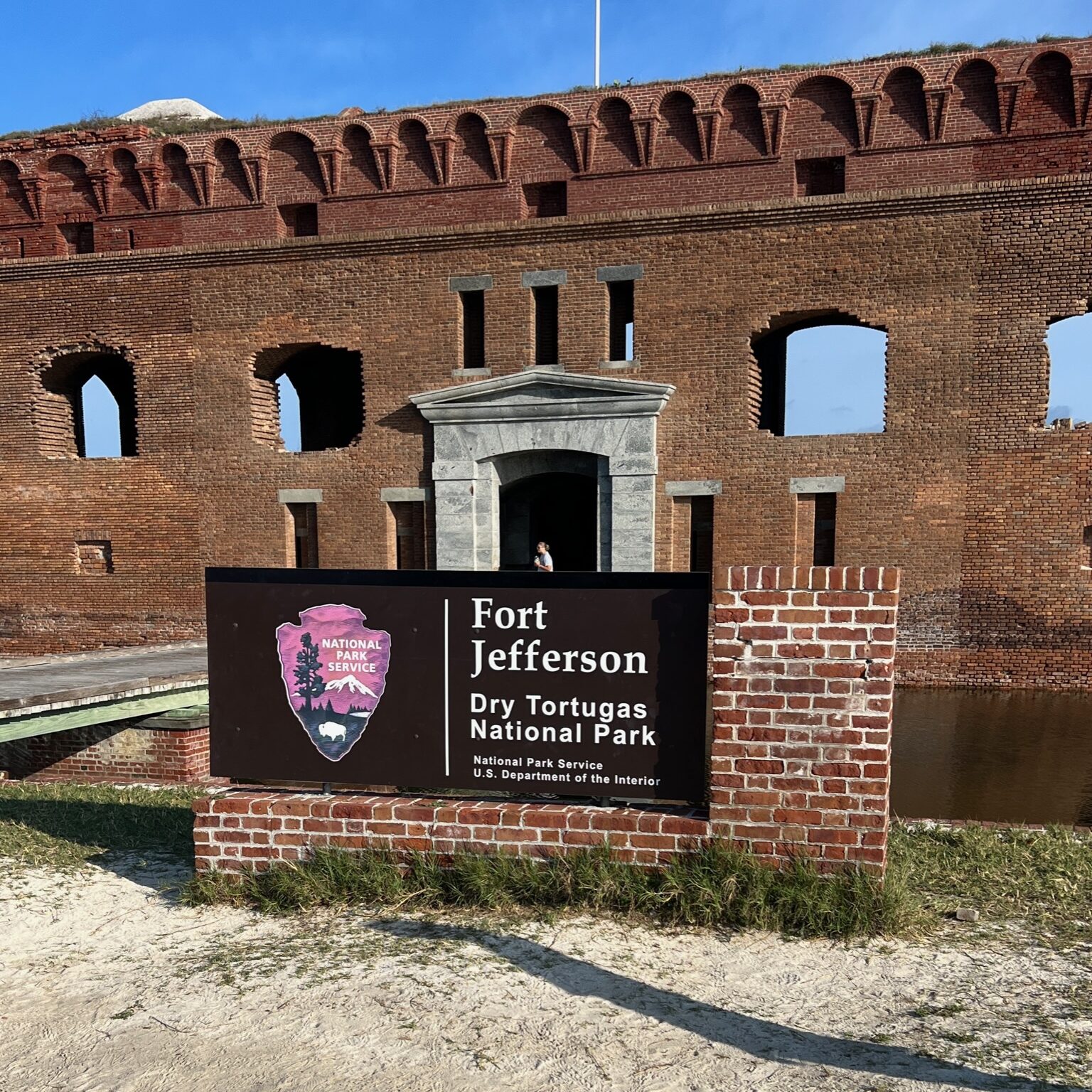 Sign for Dry Tortugas National Park with Fort Jefferson in the background, showcasing the historic fortress