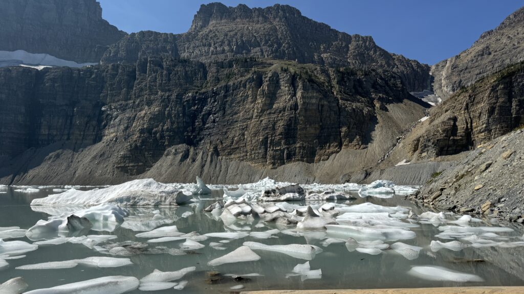 Pristine turquoise waters of Grinnell Glacier Lake surrounded by towering cliffs in Glacier National Park, a must-see destination in 2025.