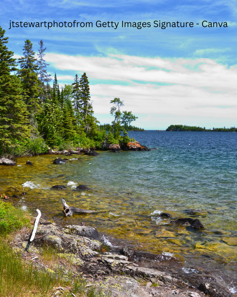 Rugged Isle Royale coastline with rocky shores, dense evergreen forests, and the vast waters of Lake Superior stretching to the horizon.