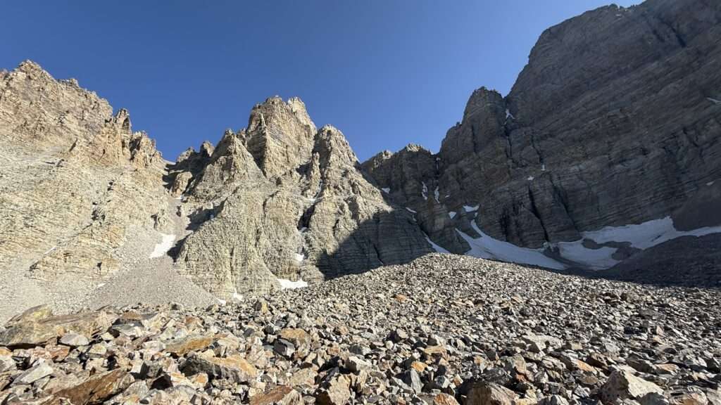 Rock Glacier nestled below the towering summit of Wheeler Peak in Great Basin National Park, with rugged alpine terrain and scattered snowfields.